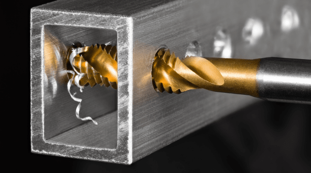 Close up of a tapping arm tap in action drilling into a square piece of metal