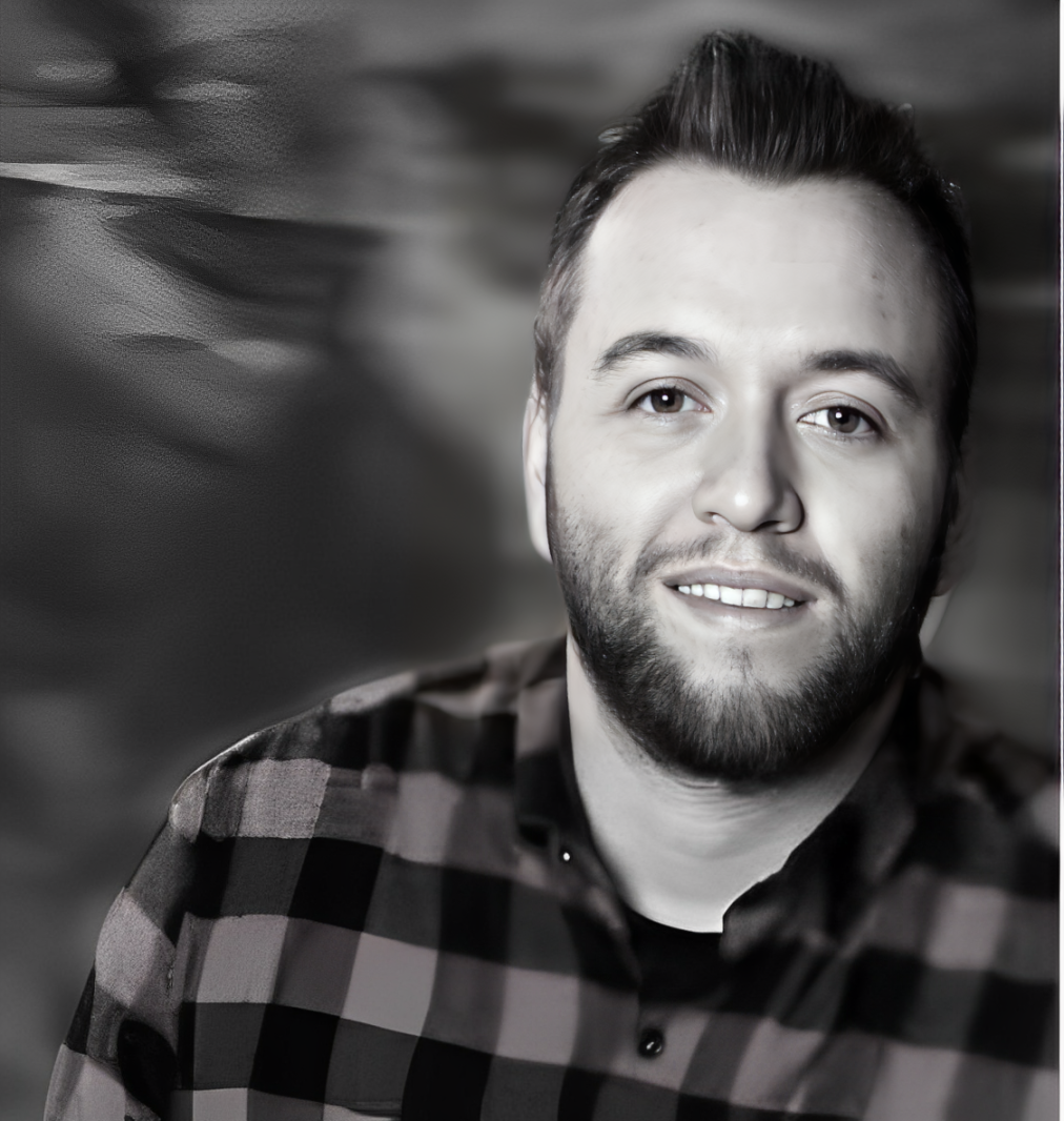 man with checked shirt smiling at the camera