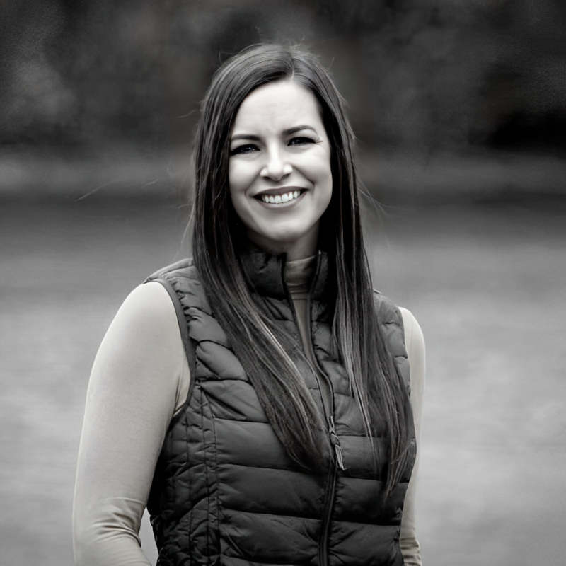 black and white portrait of woman smiling toward the camera wearing a vest