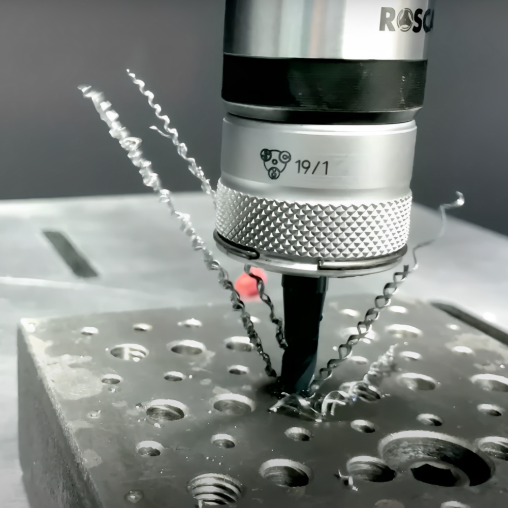 Close-up view of a Roscamat®USA tapping arm precisely drilling a hole in a metal workpiece, showcasing its adjustable modules and streamlined design for efficient tapping operations.